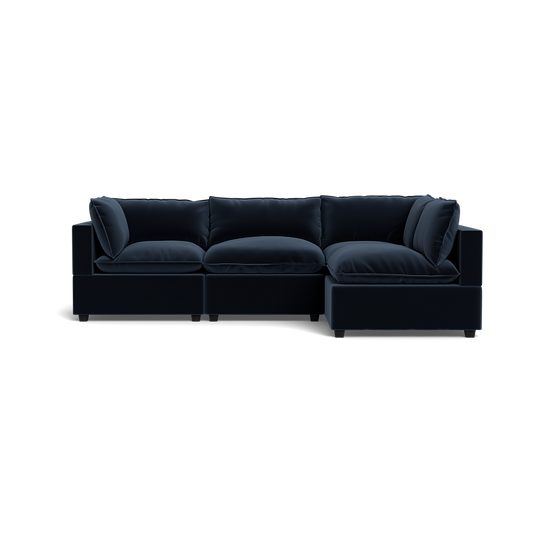 The Kova Pillow Cushion L-Shape is a modern dark navy blue sectional sofa with plush cushions and a right-side chaise, shown against a plain black background.