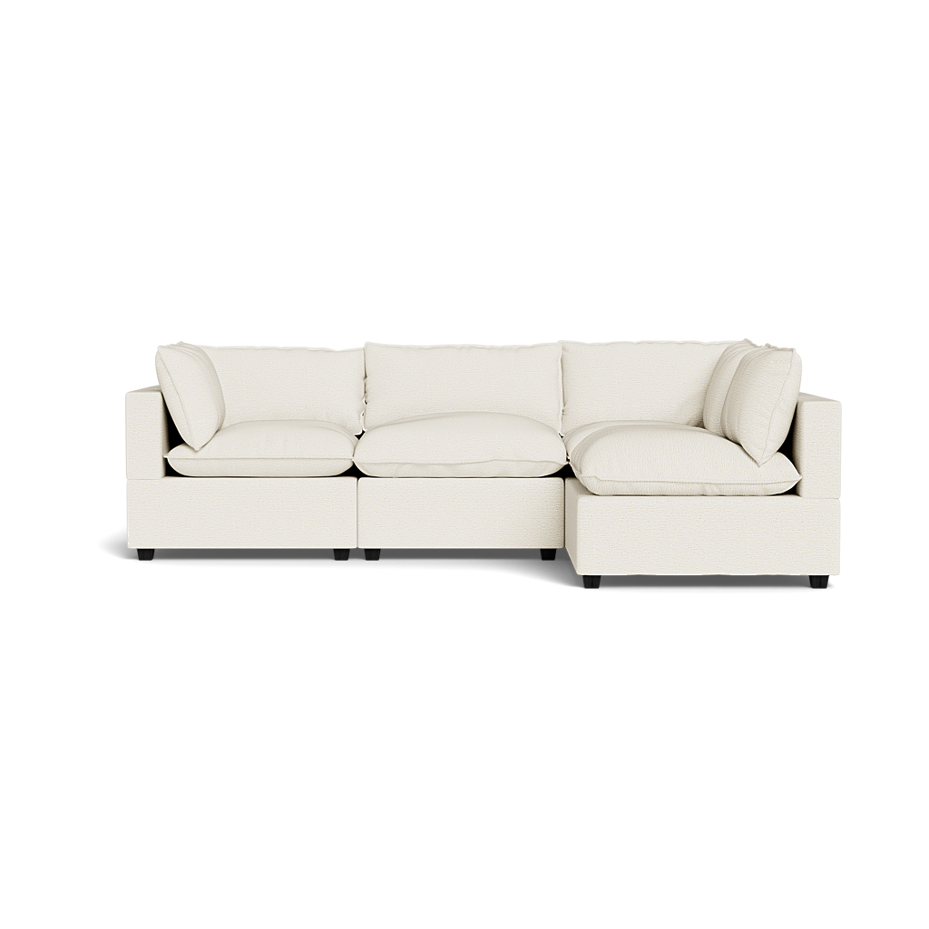 The Kova Pillow Cushion L-Shape is a modern light beige sectional sofa with plush cushions and armrests, displayed against a plain black background.