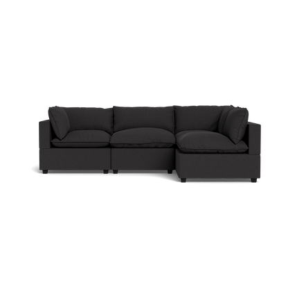 The Kova Pillow Cushion L-Shape is a modern dark grey sectional sofa with three seat, three back, and two armrest cushions, shown against a plain black background.