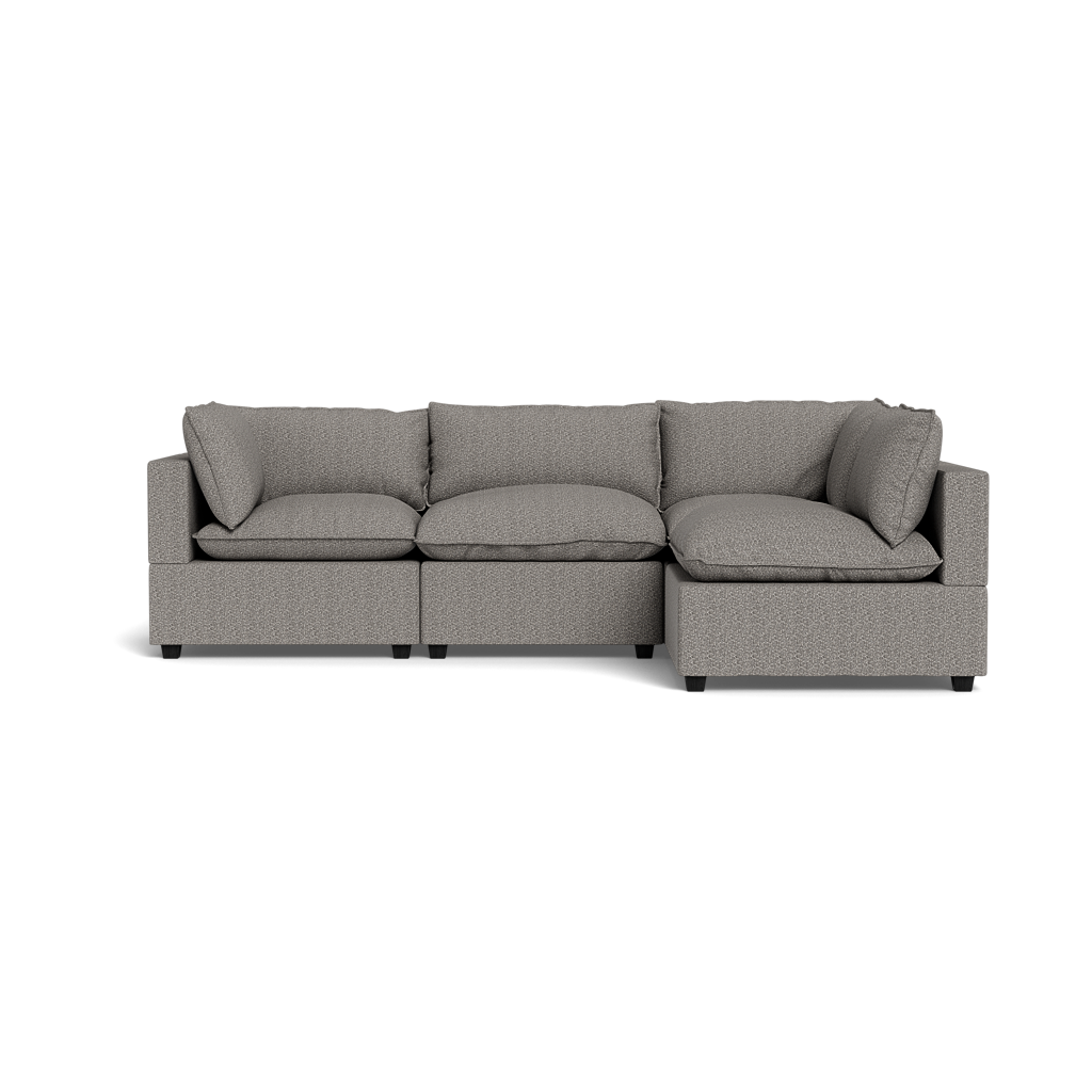 The Kova Pillow Cushion L-Shape is a modern light gray sectional with three seat cushions, three back cushions, and two armrests, displayed on a plain black background.