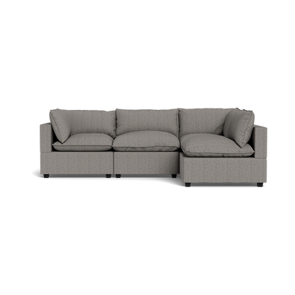 The Kova Pillow Cushion L-Shape is a modern light gray sectional with three seat cushions, three back cushions, and two armrests, displayed on a plain black background.