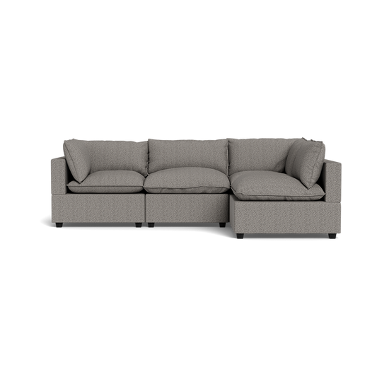 The Kova Pillow Cushion L-Shape is a modern light gray sectional with three seat cushions, three back cushions, and two armrests, displayed on a plain black background.