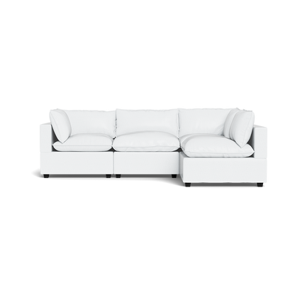 The Kova Pillow Cushion L-Shape is a modern white sectional sofa with three seat cushions and multiple matching back and side pillows, displayed against a plain black background.