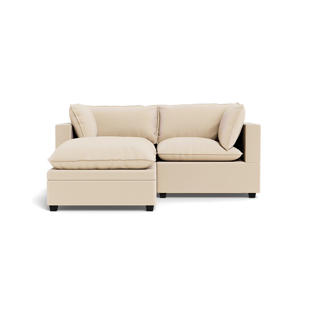 The Kova Pillow Cushion Sofa 86" with ottoman features plush beige cushions and a left-side chaise, showcased against a plain black background.