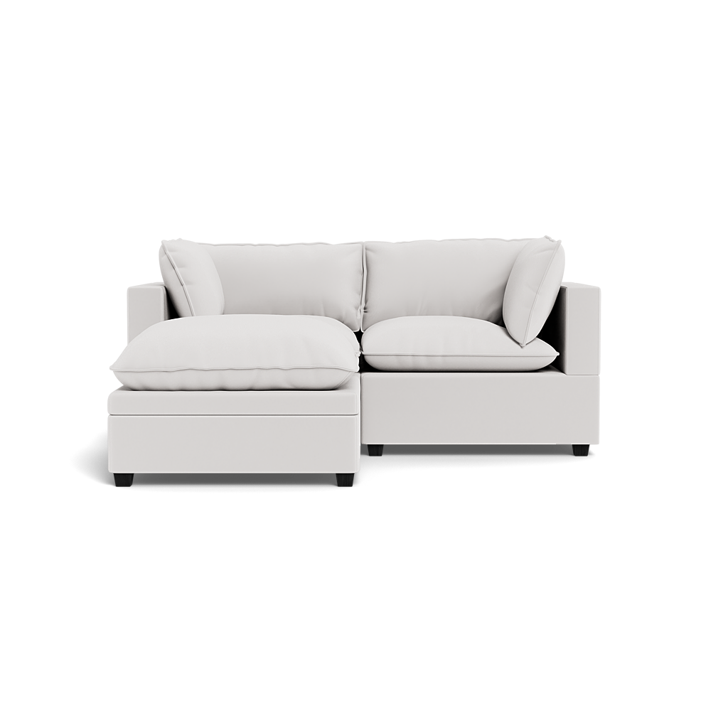 The Kova Pillow Cushion Sofa 86" + Ottoman is a modern light gray sectional with two seat cushions, plush back cushions, and armrests, displayed against a plain black background.