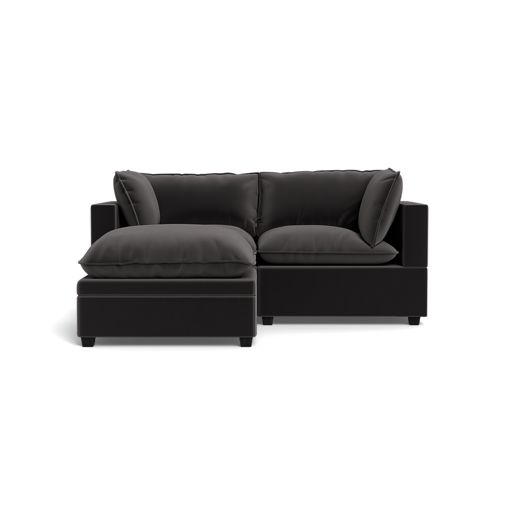 The Kova Pillow Cushion Sofa 86" with Ottoman features plush cushions and a left-side chaise, shown from the front against a plain black background.