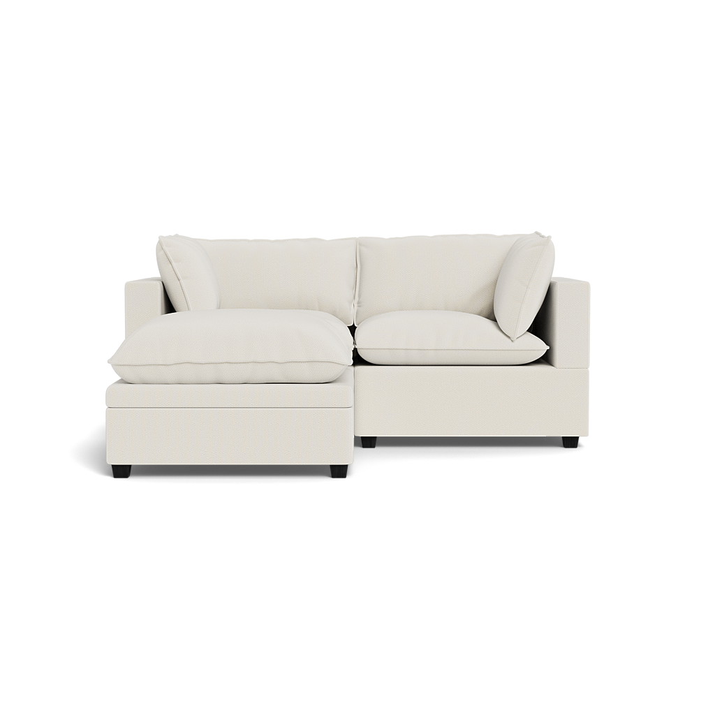 The Kova Pillow Cushion Sofa 86" + Ottoman is a modern cream-colored sectional with plush cushions, wide armrests, a left-side chaise, and a minimalist contemporary design, shown against a plain black background.