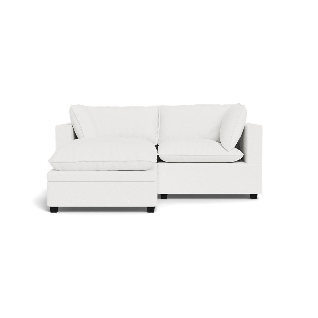 The Kova Pillow Cushion Sofa 86" with Ottoman features plush cushions and a left-side chaise, shown in modern white against a plain black background.