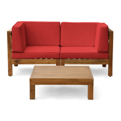 The Oana 3 Piece Love Seat Set features a two-seat sofa with red cushions and armrests, plus a low rectangular slatted coffee table—perfect for stylish outdoor lounging.