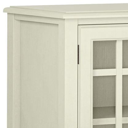 A close-up of the upper left corner of the Connaught - Handcrafted Low Storage Cabinet, showing its light wood finish, smooth top, glass-panel door with grid design, and simple classic style.