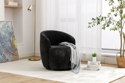 The Chenille Fabric Swivel Accent Armchair Barrel Chair with a gray throw sits on a light rug, surrounded by stacked books, a potted plant, brass floor lamp, leafy plant, and abstract painting. Sunlight filters through sheer curtains.