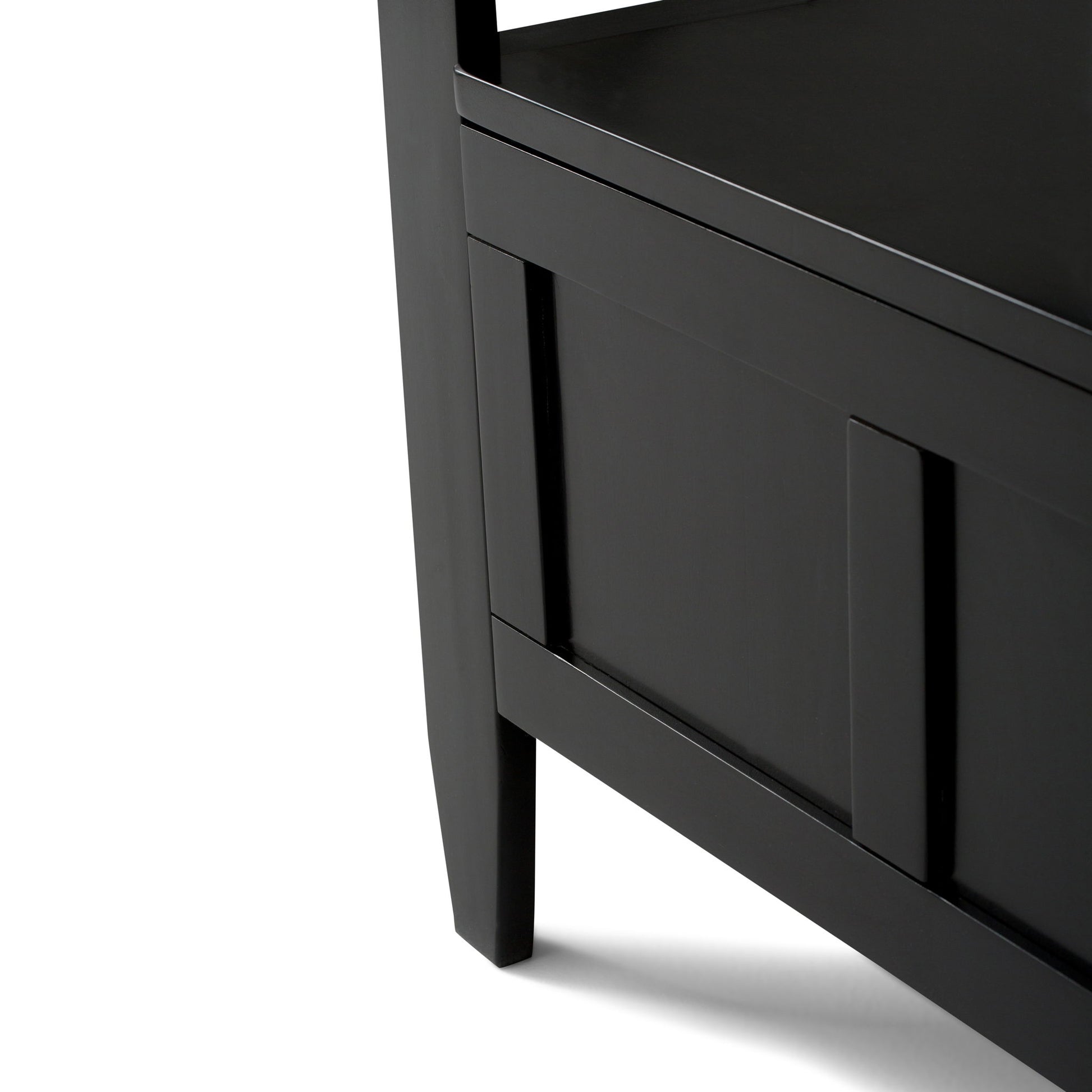 Close-up of the lower corner of the Brooklyn - Handcrafted Entryway Storage Bench, featuring black wood, clean lines, and panel detail. The bench casts a shadow on a white background.