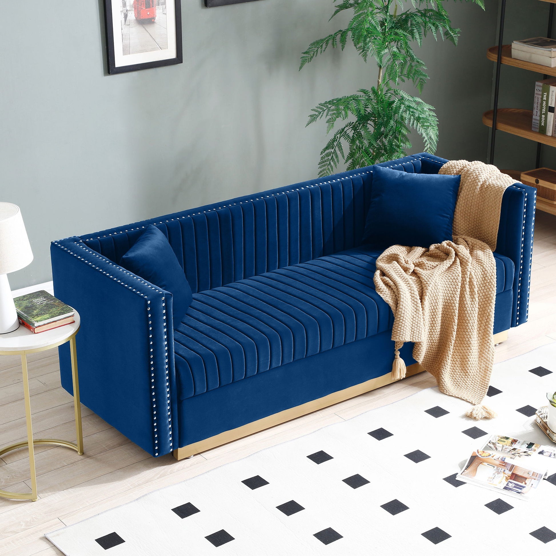 A Contemporary Vertical Channel Tufted Velvet Sofa Loveseat 2-piece set with 4 pillows is arranged in a stylish living room, featuring soft blue upholstery and elegant detailing. A beige throw and nearby decor complete the cozy, modern scene.