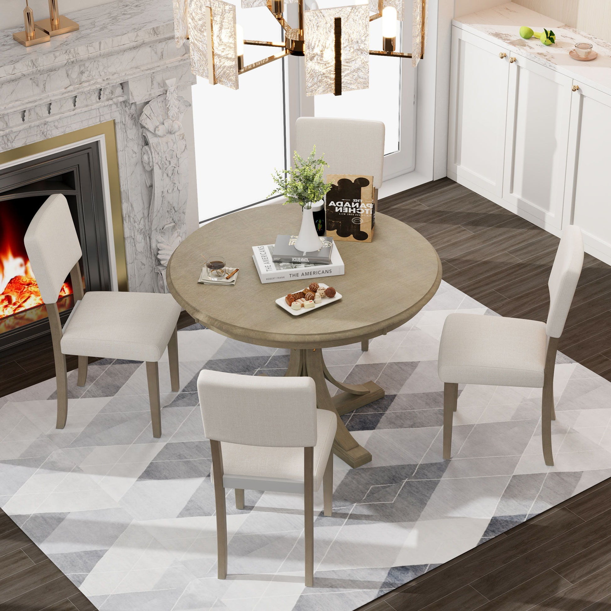 The Retro Round Dining Table Set with curved trestle legs and upholstered chairs is arranged on a geometric rug in a modern room featuring dark floors, a marble fireplace, white cabinets, and a chandelier above the table.