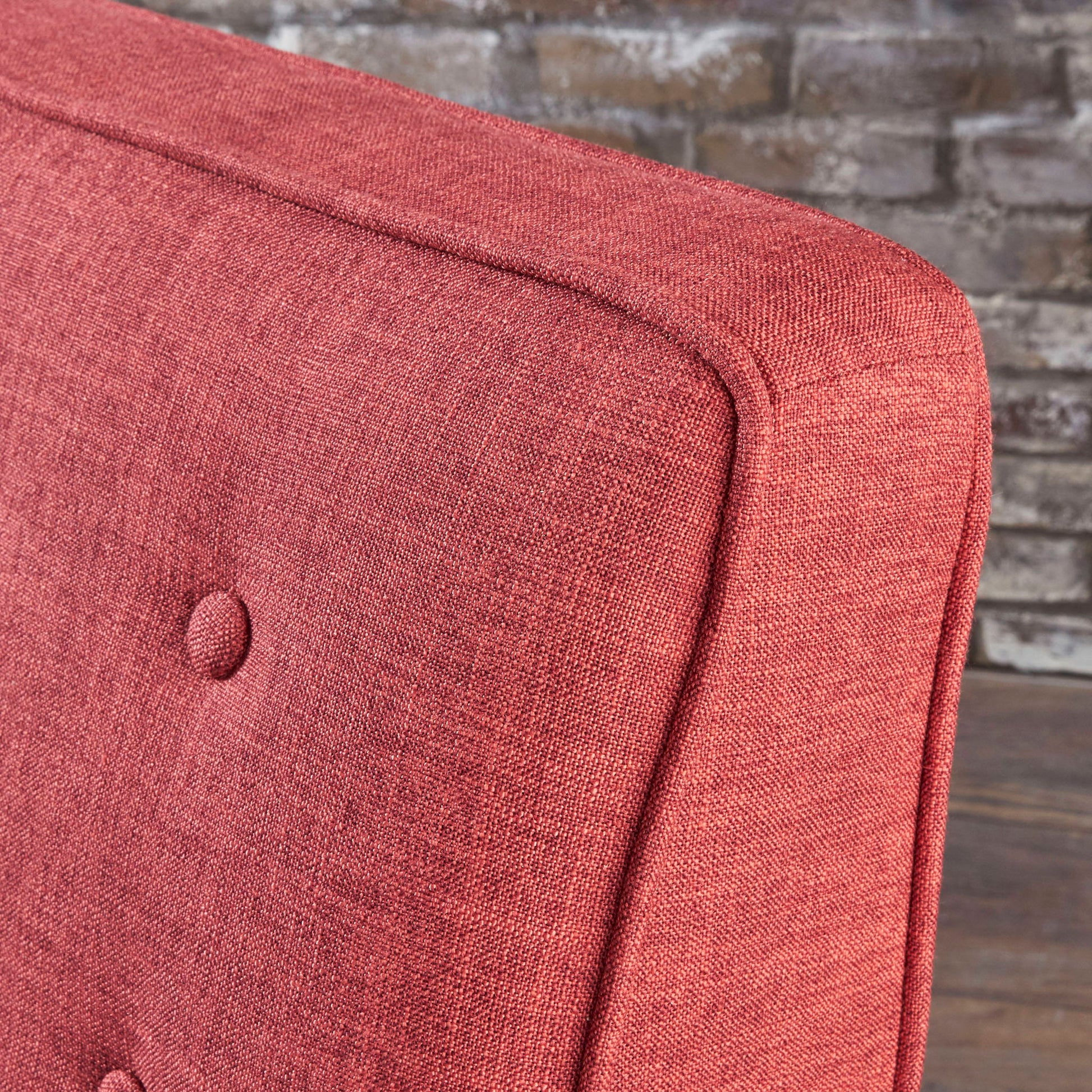 Close-up of the backrest of the Mid-Century Modern Recliner With Button Tufted Waffle Stitch in red upholstery, shown against a brown brick wall and wooden floor.