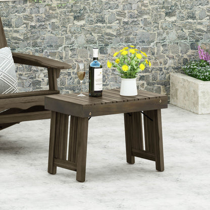 The Temptation Outdoor Foldable Side Table With Slat Design holds a wine bottle, wine glass, and a vase of yellow flowers. A cushioned chair is partly visible on the left with a stone wall in the background.