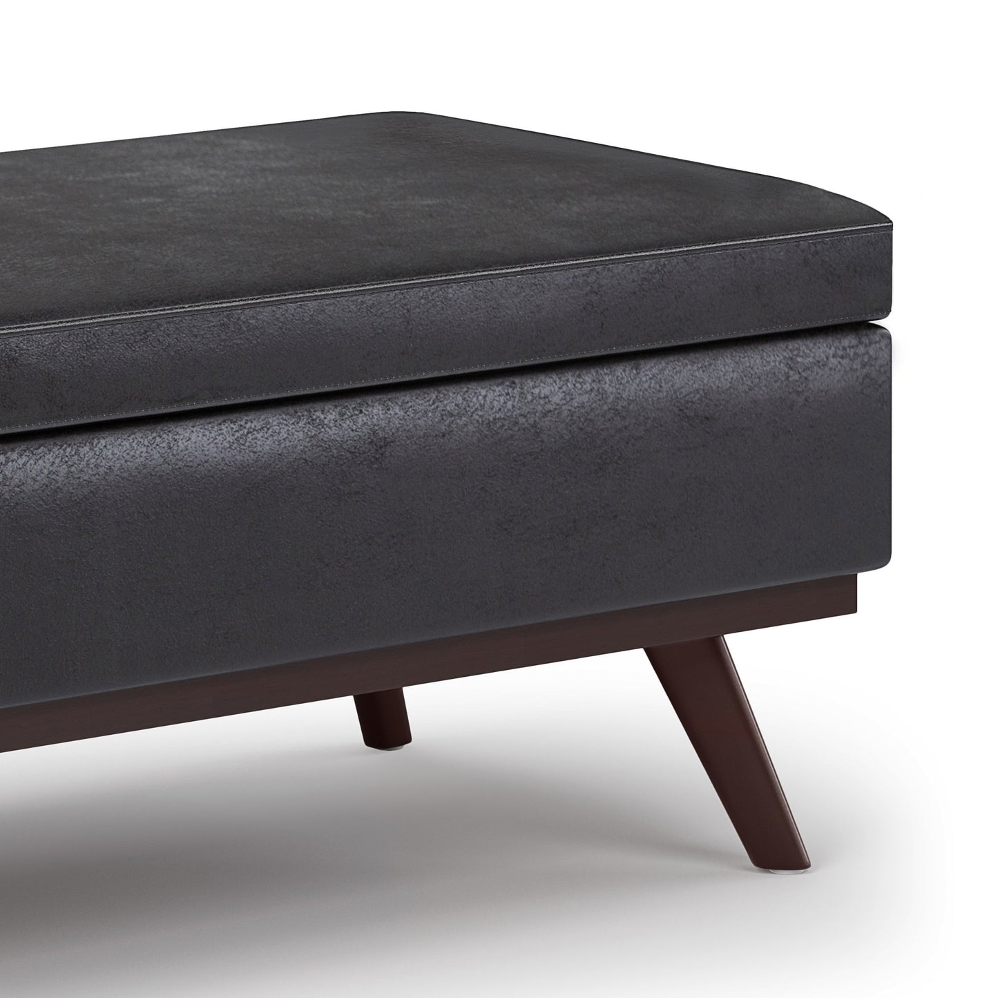 Close-up of the Owen Lift Top Large Coffee Table Storage Ottoman, featuring a black textured cushion and angled dark wooden legs in mid-century style, shown on a white background.