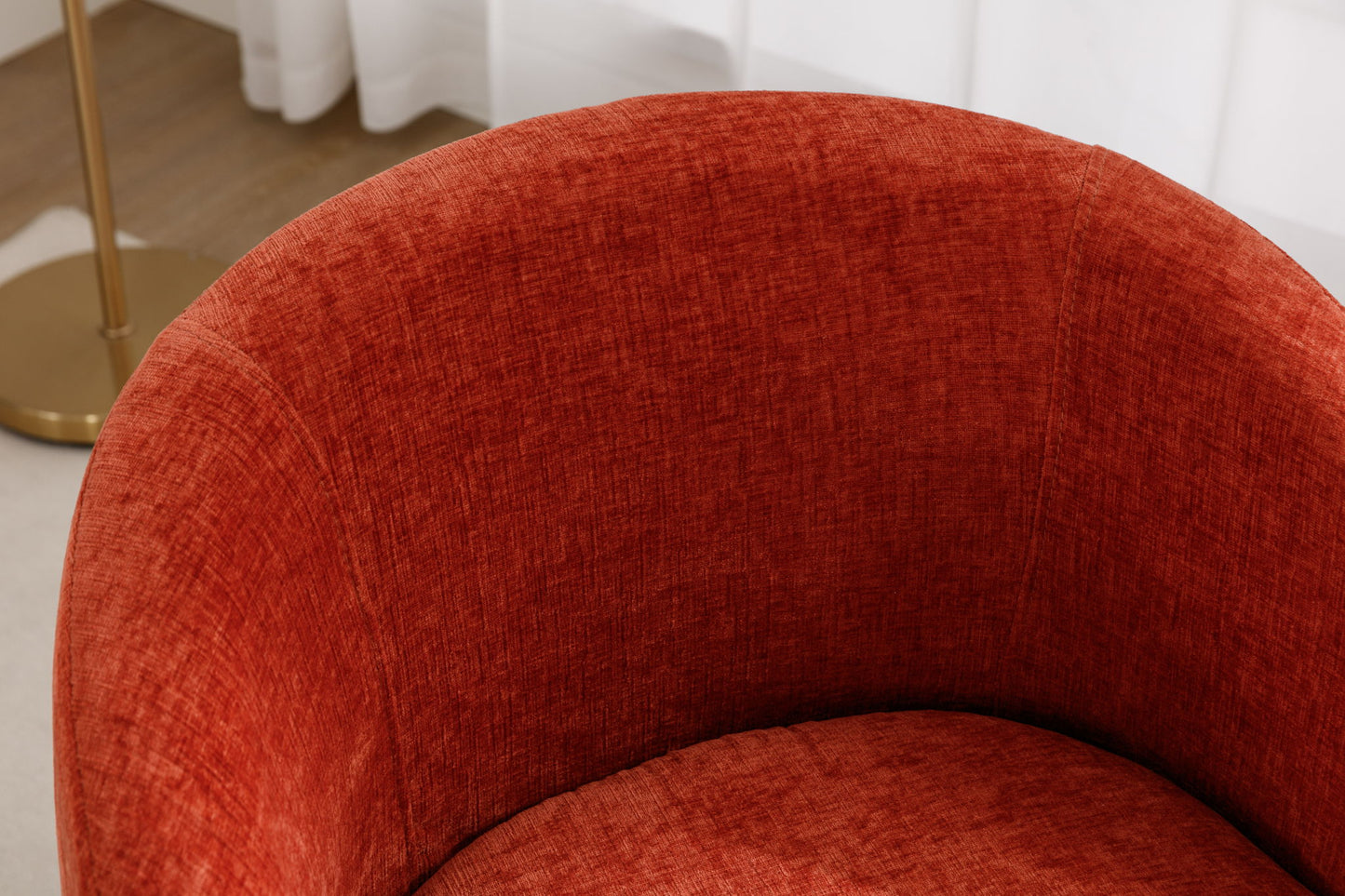 A close-up of the Chenille Fabric Swivel Accent Armchair Barrel Chair with a powder-coated metal ring, upholstered in textured red fabric, alongside a gold floor lamp and white curtains in the background.