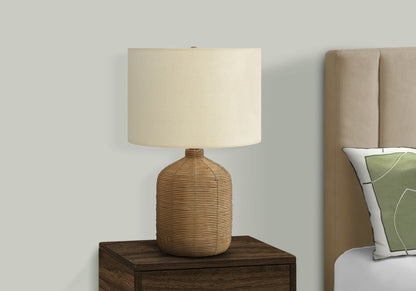 A modern rattan table lamp sits on a nightstand beside a bed with a tan upholstered headboard and a green and white decorative pillow.