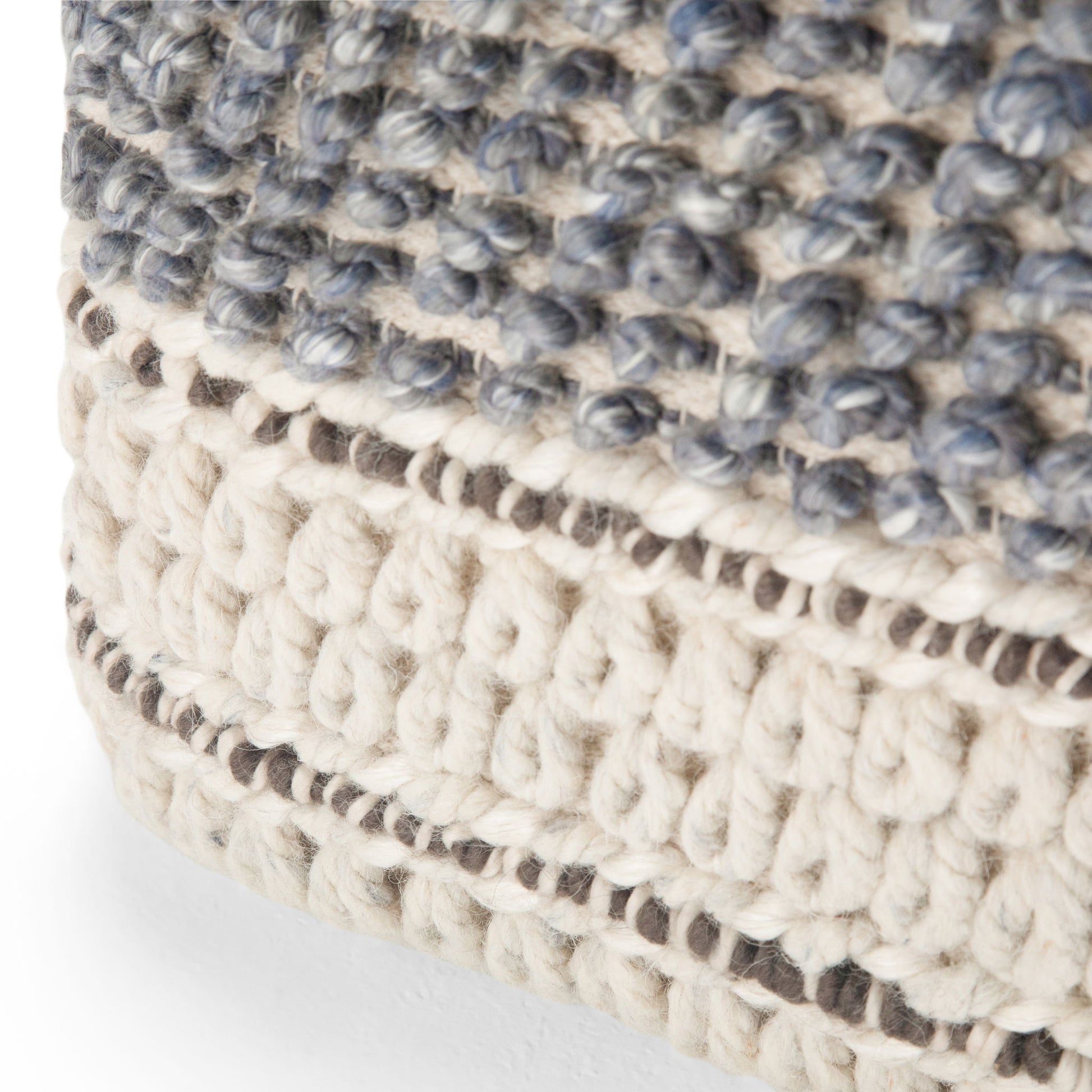 Close-up of the Grady - Handcrafted Square Pouf, featuring chunky cream and gray yarn in a striped and knotted design, highlighting its textured, cozy fabric and detailed craftsmanship.
