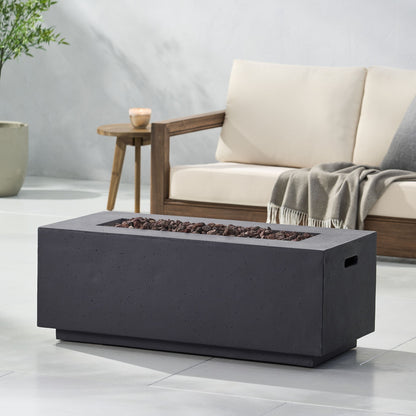 A modern patio featuring a beige cushioned sofa, gray throw blanket, and the Contemporary Outdoor 40,000 Btu Propane Fire Pit with lava rocks on light gray tile flooring. A potted plant sits in the background.
