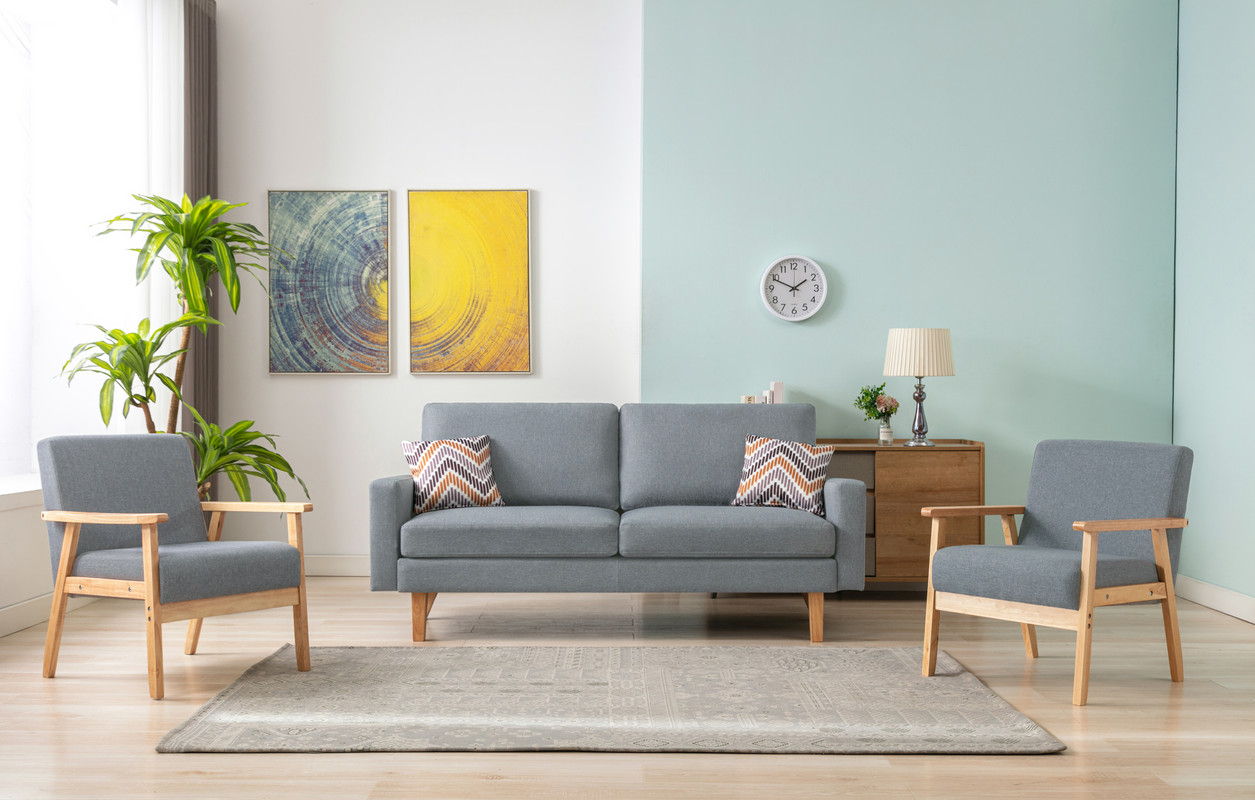 A modern living room featuring the Bahamas Sofa Set with 2 Throw Pillows, a gray sofa, two matching wooden-arm chairs, a light blue accent wall, rug, potted plant, sideboard, lamp, clock, wall art, and geometric-patterned pillows.