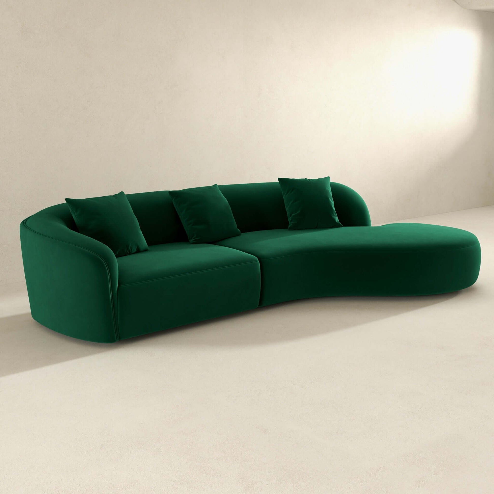 The Elijah Japandi Style Curvy Sectional Sofa in green, with four matching cushions, rests on a light minimalist floor against a plain off-white wall.