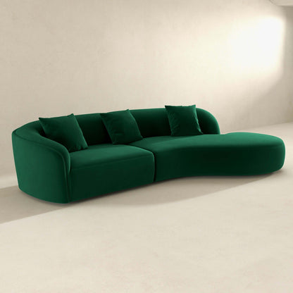 The Elijah Japandi Style Curvy Sectional Sofa in green, with four matching cushions, rests on a light minimalist floor against a plain off-white wall.