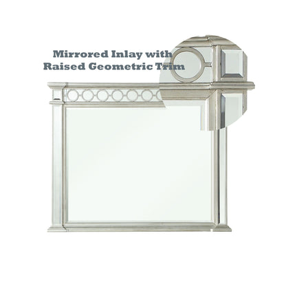The Varian Mirrored Designed Mirror in Silver features a rectangular shape with decorative mirrored inlays and raised geometric trim, accented by a circular inset that highlights the stylish design. Text above reads: "Mirrored Inlay with Raised Geometric Trim.