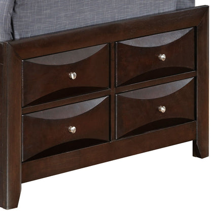 The Marilla Storage Bed With Bookcase Headboard features a dark wood footboard with four rectangular drawers, each adorned with a silver knob and wave-like front design. A gray upholstered mattress is partially visible on top.
