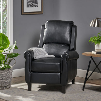 The Contemporary Push Back Recliner Chair in black leather, draped with a gray patterned blanket, sits on a light rug beside a green potted plant and a wooden side table with a lamp and another plant in a cozy gray room.
