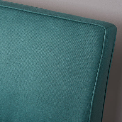 Close-up of the upper corner of the Contemporary Loveseat With Upholstered Fabric And Birch Wood Legs in teal, set against a light gray wall.