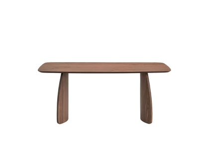 The Hadasa - Dining Table - Walnut features a modern, rectangular wooden design with rounded edges and two wide, curved legs at each end, displayed on a plain white background.
