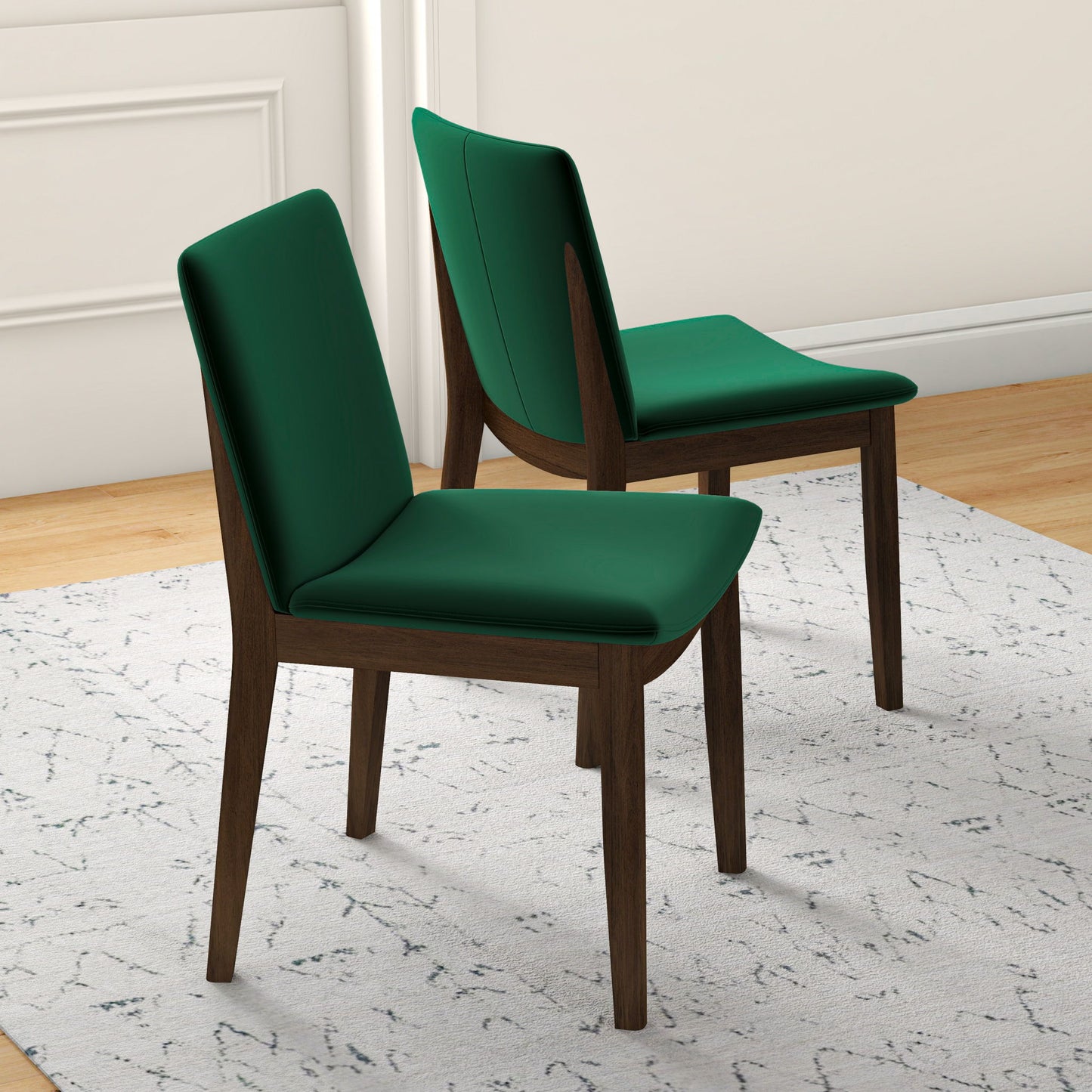The Laura Mid-Century Modern Solid Wood Dining Chairs (set of 2) feature dark wooden frames and green upholstered seats and backs, positioned on a light-patterned rug atop light wood flooring beside white walls.