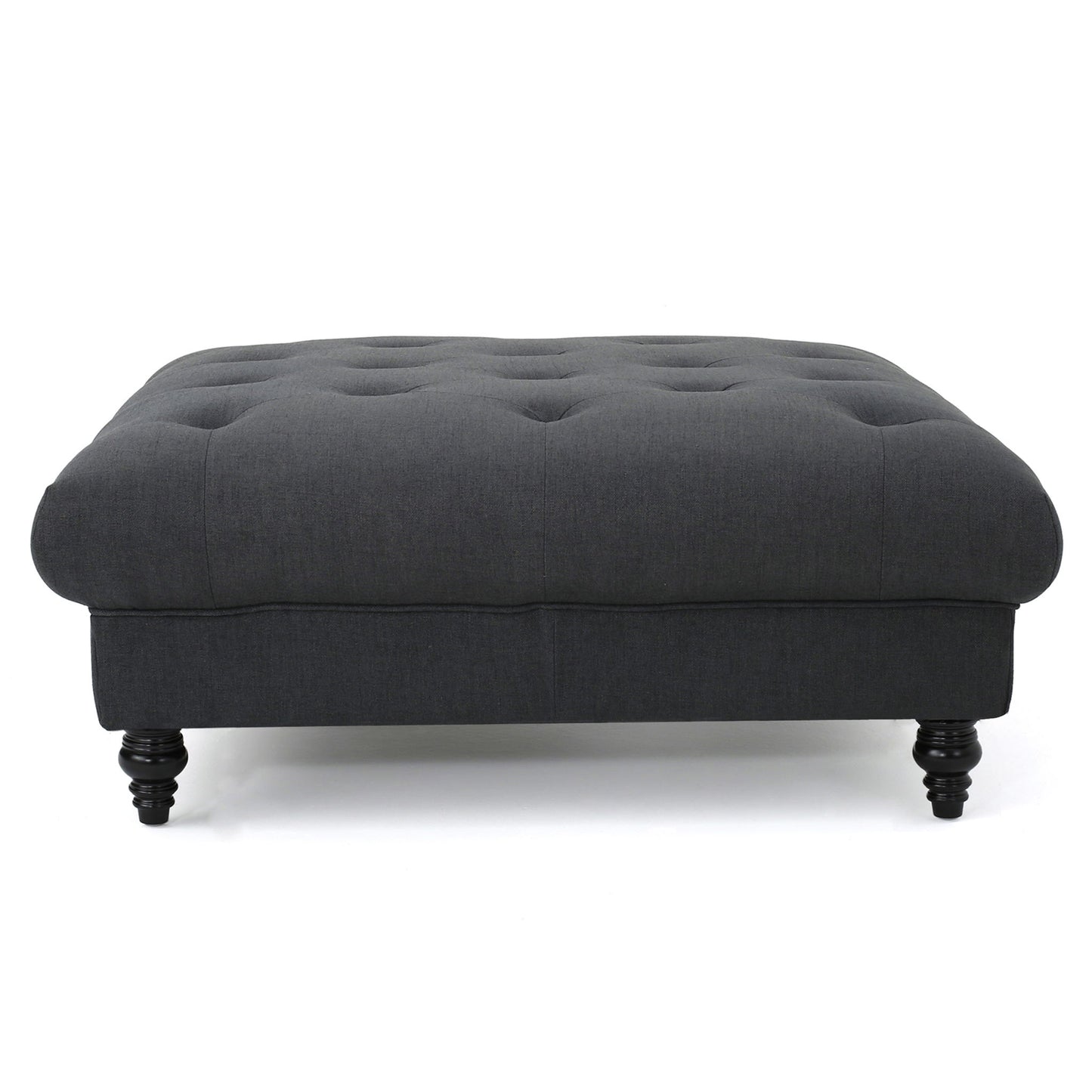 The Madrid - Tufted Ottoman Footrest is a dark gray, rectangular piece with a tufted top and four short, turned wooden legs, displayed against a white background.