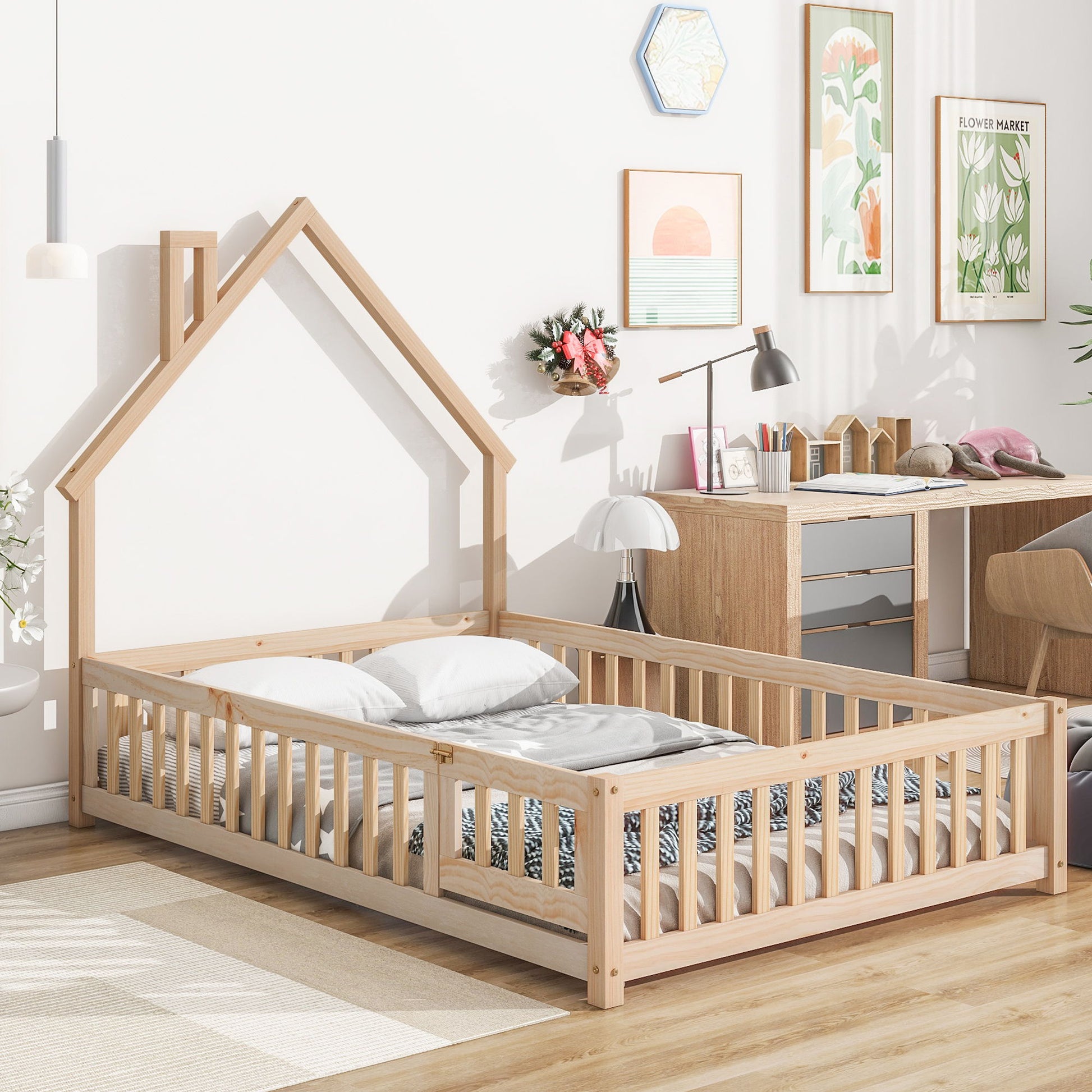 A cozy kids’ room highlights the House-Shaped Headboard Floor Bed With Fence, styled with white bedding, a study desk, books, wall art, plants, and natural sunlight streaming through the window.