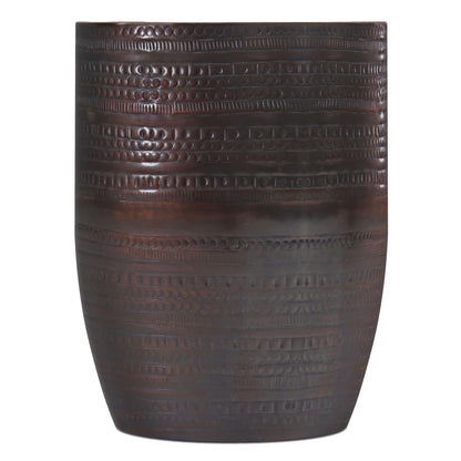 The Johnsen Handcrafted Large Metal Accent Table is dark brown, cylindrical, and features a textured surface with horizontal patterns of raised dots and rectangles.