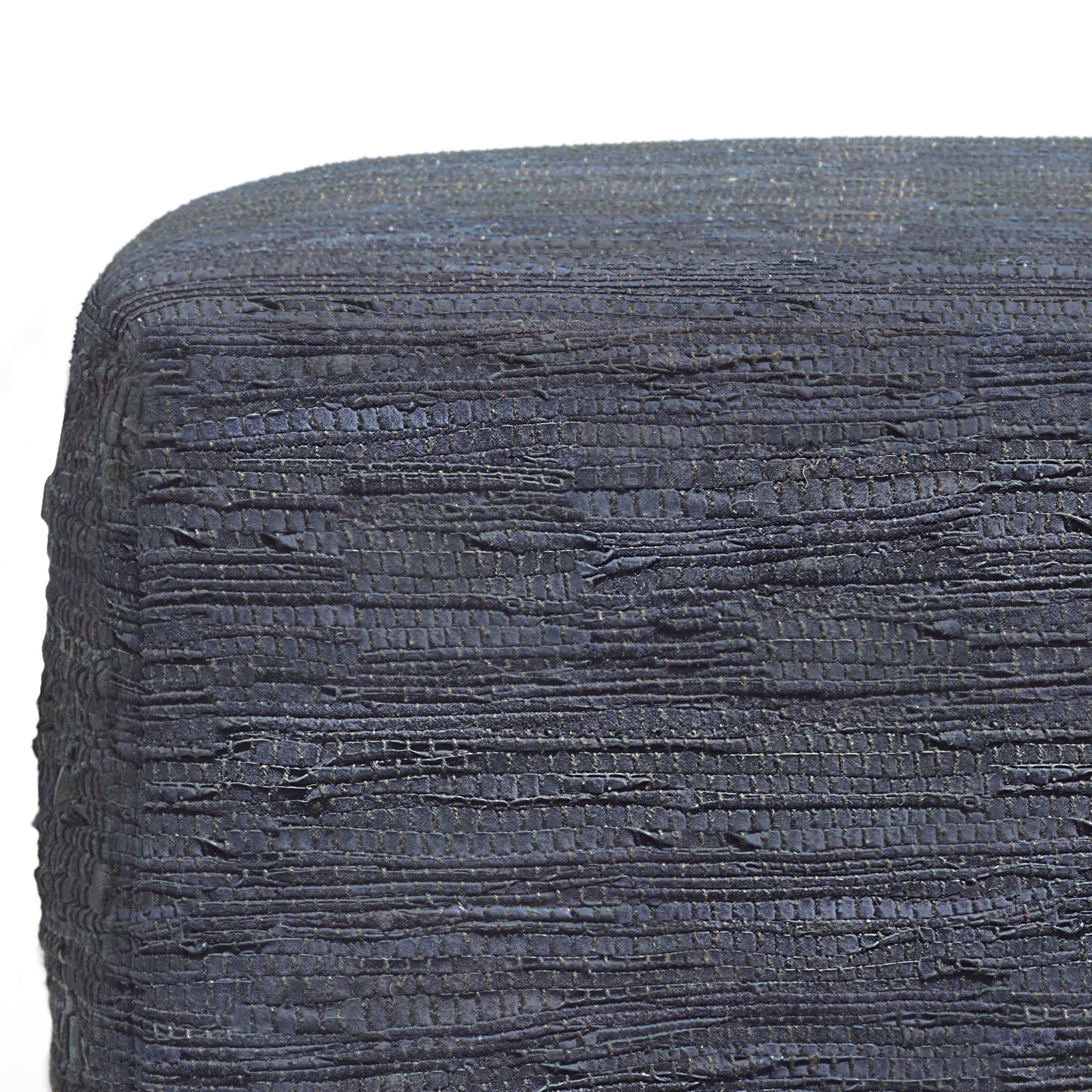 Close-up of Fredrik - Handcrafted Square Pouf in dark blue textured fabric with uneven horizontal stitches, tightly wrapped around its edge. The background is plain white.