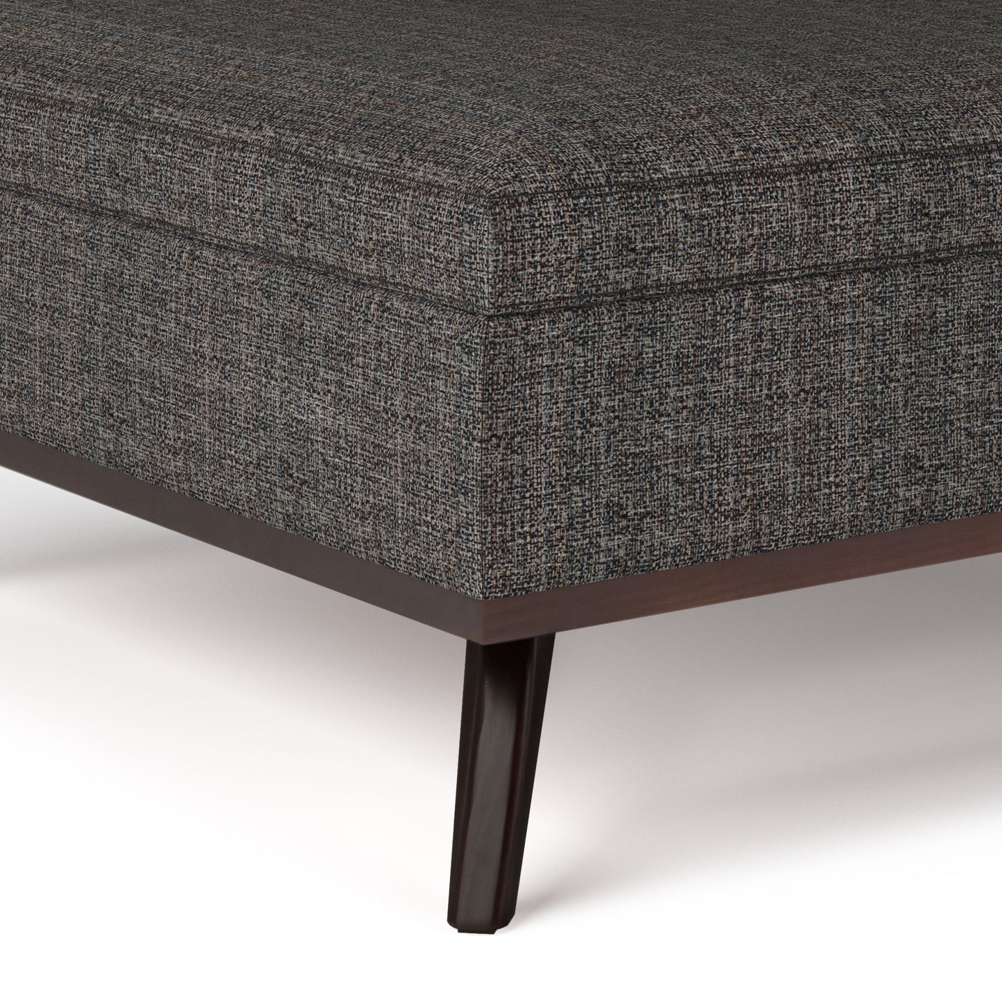Close-up of the corner of the Owen - Multifunctional Square Coffee Table Storage Ottoman in dark gray upholstery with a subtle textured fabric and wooden legs, shown against a white background.