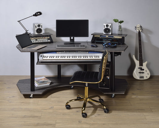 The Eleazar Music Recording Studio Desk in wood holds a computer, keyboard, speakers, headphones, synthesizers, lamp, plants, and sits beside a white electric bass guitar and black-gold swivel chair on a wooden floor.