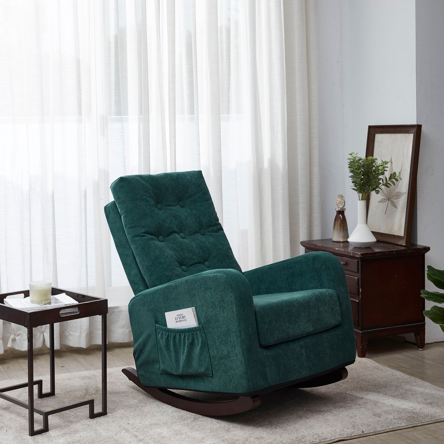 A Single Sofa Reclining Japanese Chair, upholstered in green, with a side pocket, is placed near a window with sheer curtains in a bright living room. Nearby are a small table holding a candle and a wooden cabinet decorated with ornaments.