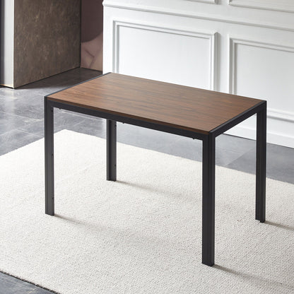 The Creative Design Veneered MDF Wood Structure Rectangular Walnut Dining Table stands on a light-colored rug in a room with gray tile floors and white paneled walls, featuring black metal legs.