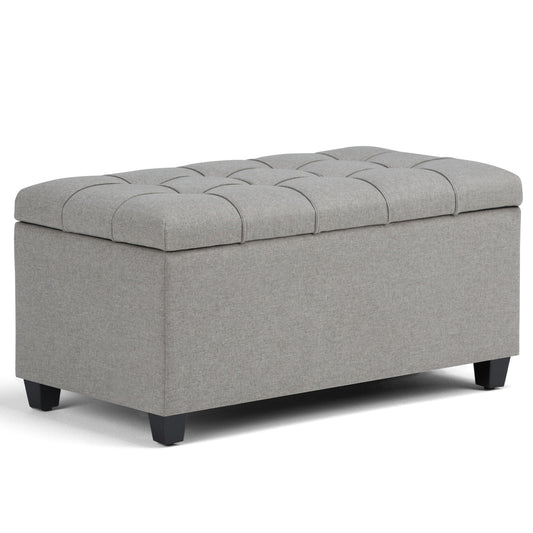 The Sienna Upholstered Storage Ottoman Bench is rectangular, light gray with a tufted top and short black legs, shown on a white background.