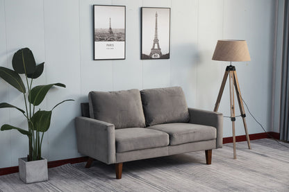 A modern living room featuring the Comfortable Loveseat With Durable Construction in gray, a tall potted plant, a tripod floor lamp, and two framed Eiffel Tower pictures on a light-colored wall.