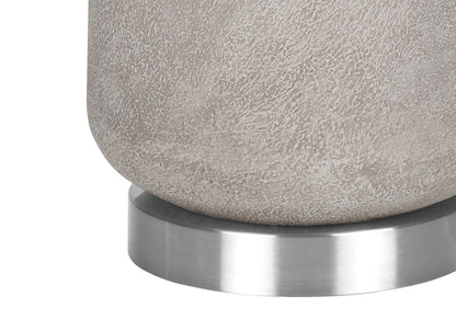 A close-up of the base of the Lighting Table Lamp in modern gray resin, featuring a textured cylindrical design and resting on a smooth, round metallic platform.