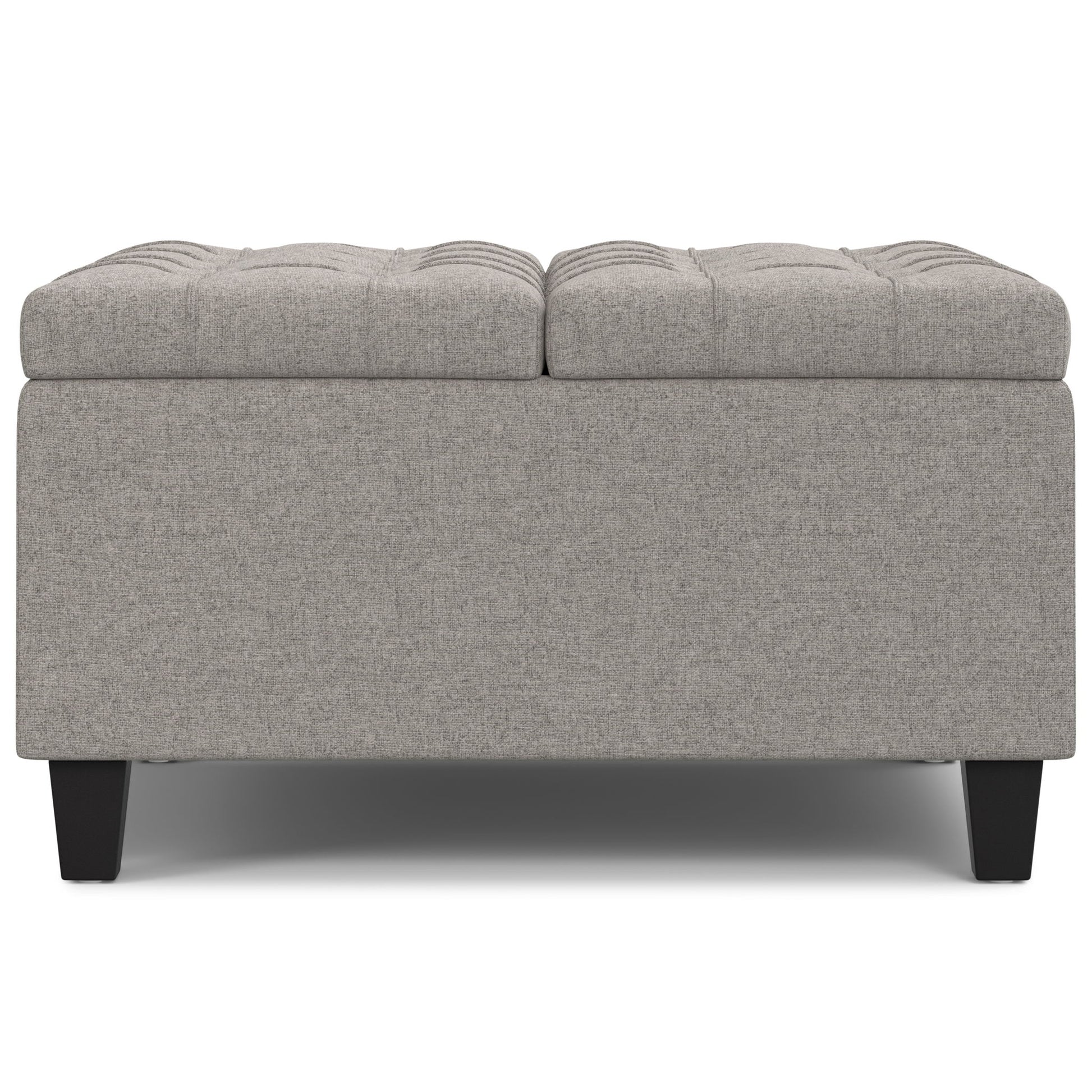 The Harrison Upholstered Coffee Table Storage Ottoman features a rectangular gray tufted top and short black legs, displayed from the front on a white background.