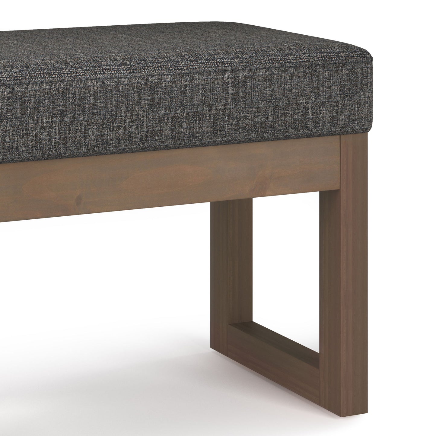 A close-up view of the Milltown Upholstered Ottoman Bench, featuring a dark grey upholstered cushion and a wooden base with straight, rectangular legs.
