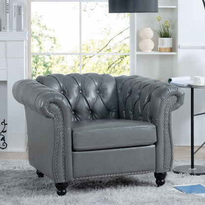 The 1 Seater Sofa For Living Room features gray tufted leather, rolled arms, and nailhead trim, set in a bright space with white shelves, decor accents, and a large window revealing greenery outside.