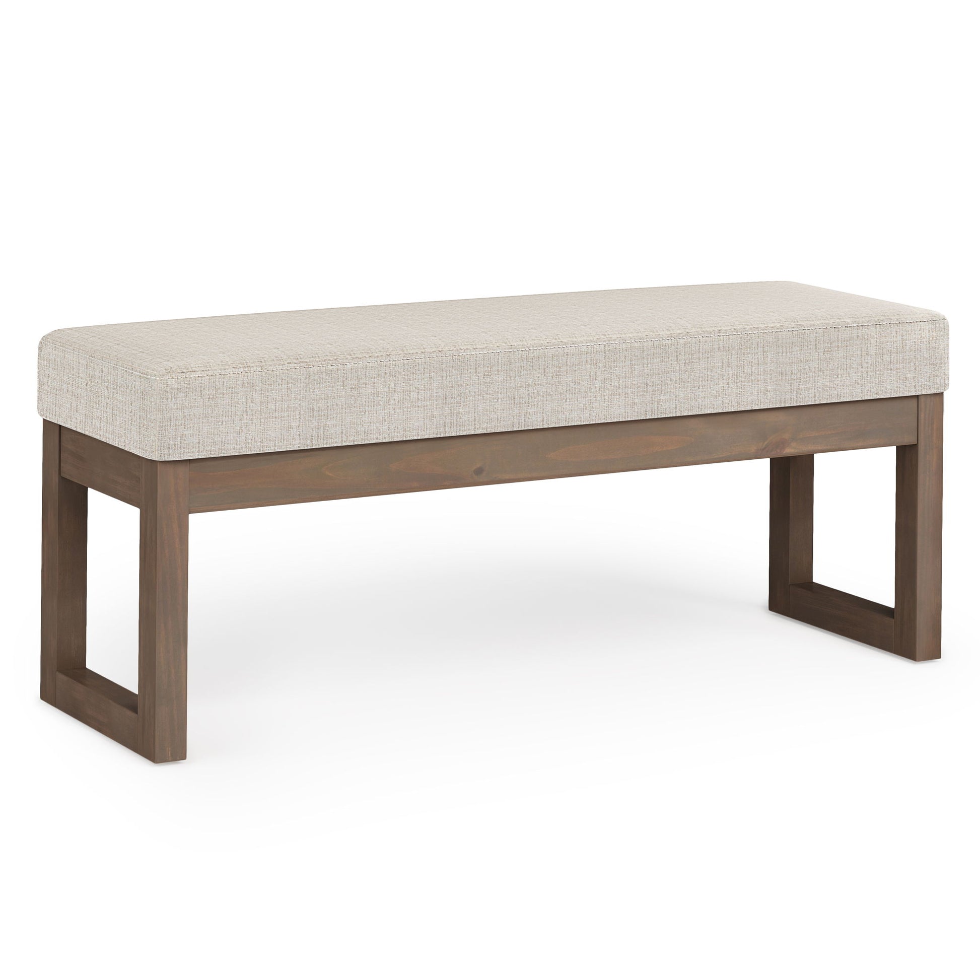 The Milltown Upholstered Ottoman Bench features a rectangular beige upholstered seat and simple open wooden legs, displayed against a white background.