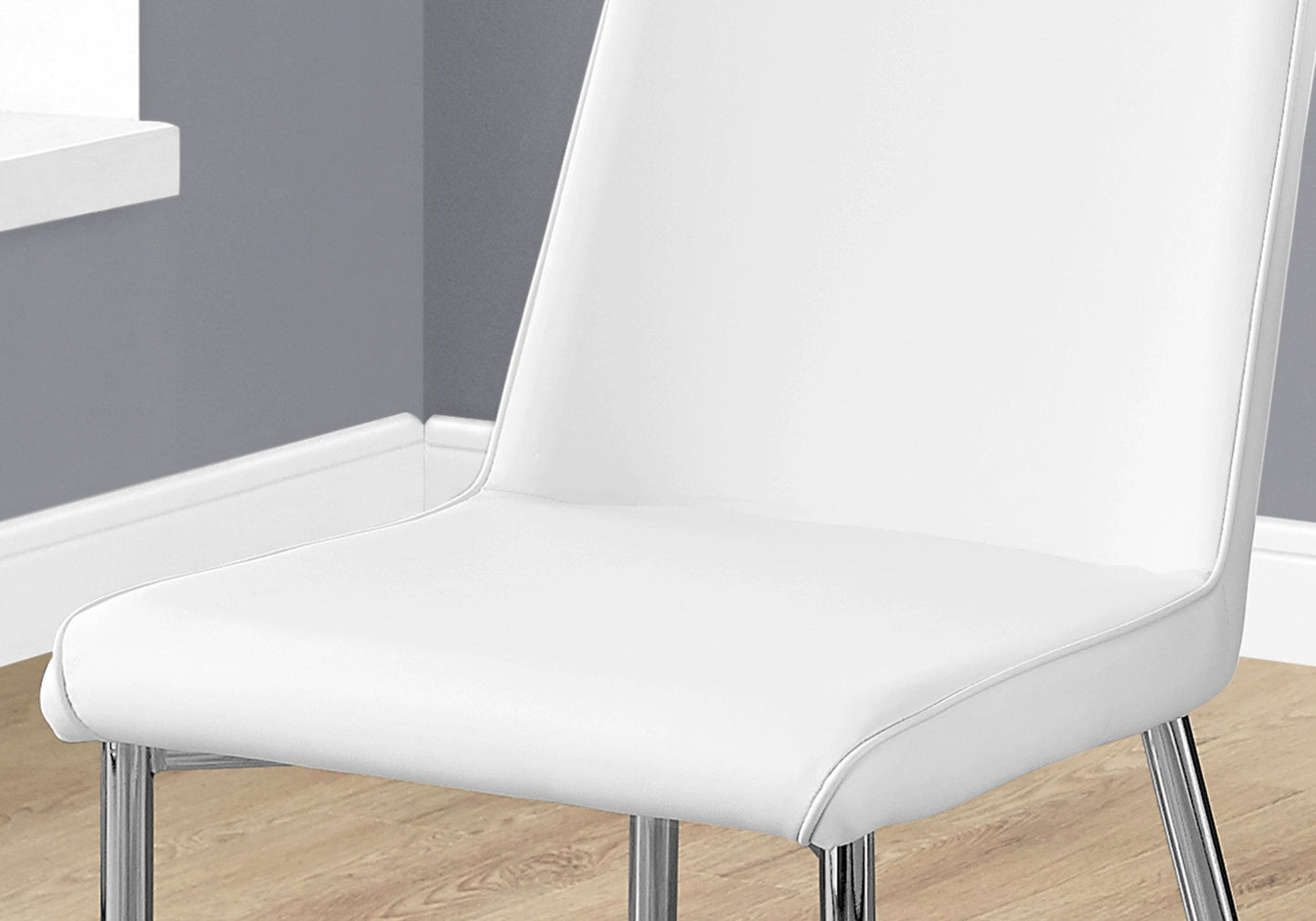 A set of 2 contemporary upholstered dining side chairs with chrome legs is placed on a light wood floor in a room with gray walls and white trim.